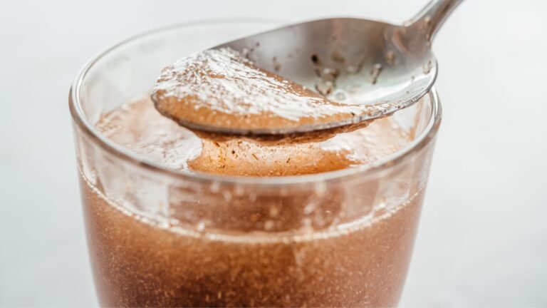 Cucchiaino che prende da un bicchiere fibra solubile disciolta in acqua. Sarà convertita dai batteri intestinali in acidi grassi a catena corta