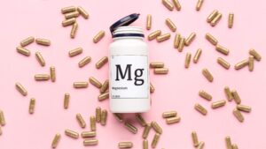 flacone di plastica con etichetta che indica il magnesio (Mg) con capsule intorno