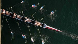 Foto dall’alto di quattro persone in una canoa a remi durante una gara di canottaggio, esempio di sforzo intenso che utilizza la glicolisi anaerobica