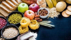 Tavola con diversi alimenti tra cui pasta, farina, frutta, legumi, pane. Tutti contenenti carboidrati