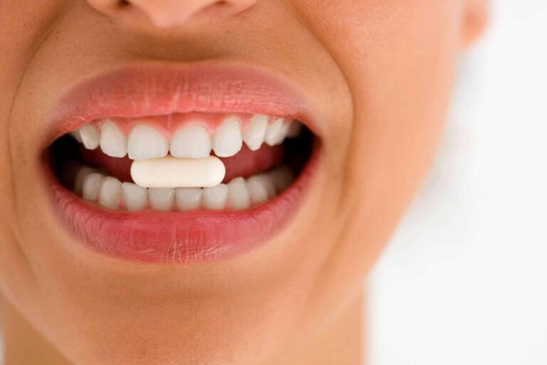 Donna che tiene capsula tra i denti bianchi contenente sali di magnesio