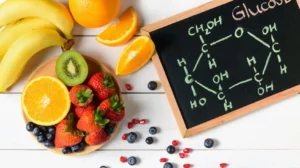 Frutta fresca ricca di glucosio accanto alla formula chimica del glucosio disegnata su una lavagna