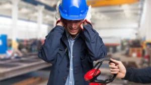 un uomo a lavoro si copre le orecchie perché c'è troppo e gli porgono delle cuffie per aiutarlo a combattere l'inquinamento acustico