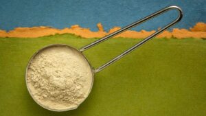 Pentolino con polvere di ashwagandha su sfondo verde e blu