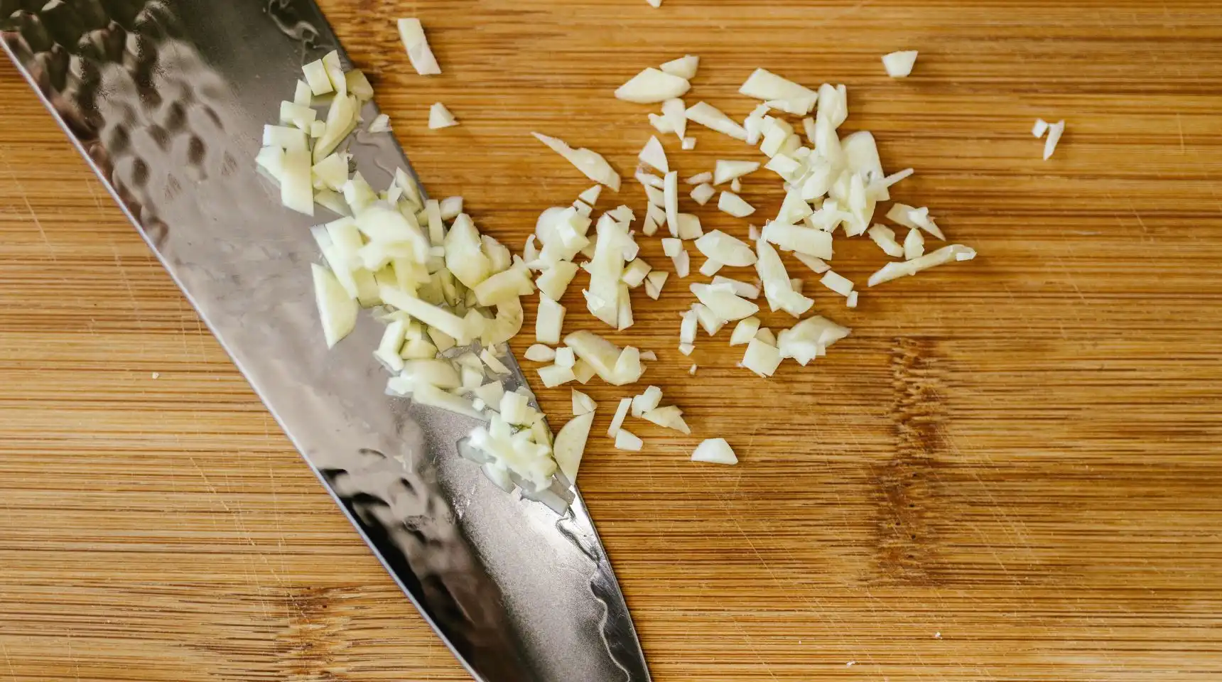 Aglio fresco tritato su tagliere con coltello