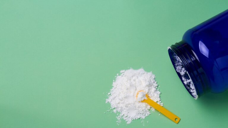 Barattolo rovesciato e polvere di creatina su sfondo verde