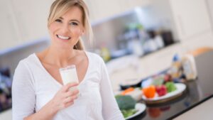Donna che beve un bicchiere di latte con caseina A2, fonte proteica digeribile e funzionale