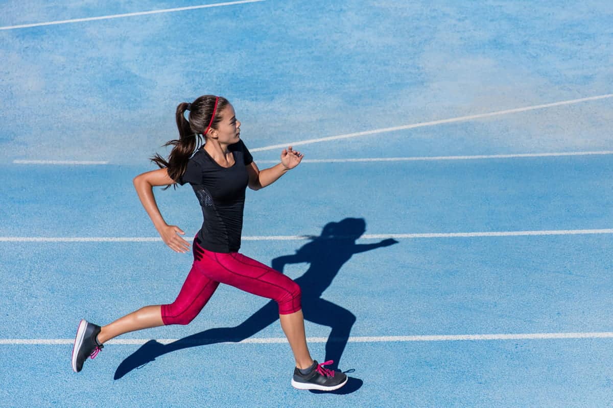 Donna che corre in pista blu durante l’allenamento, simbolo di resistenza e miglioramento del VO2max