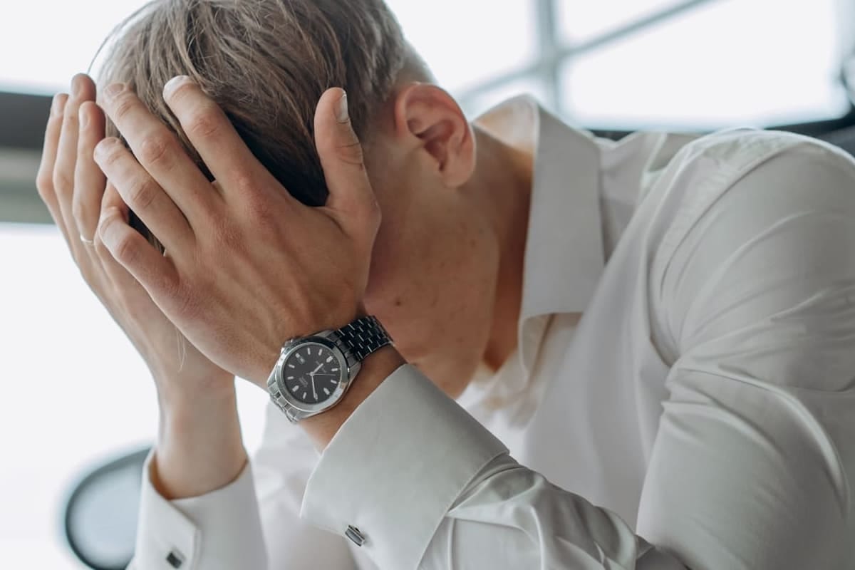 Uomo con la testa tra le mani che mostra segni di stanchezza mentale e stress