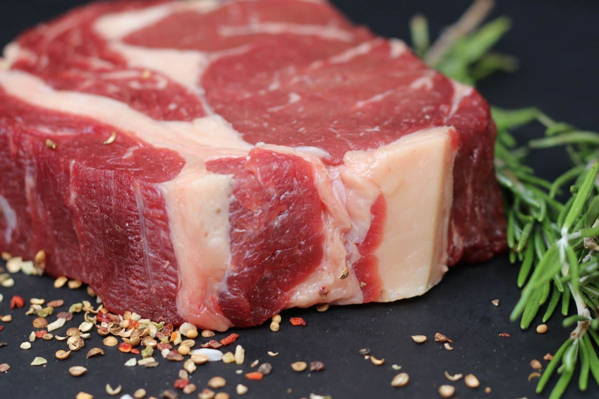 Fetta di carne rossa con rosmarino e spezie, simbolo delle proteine animali di qualità