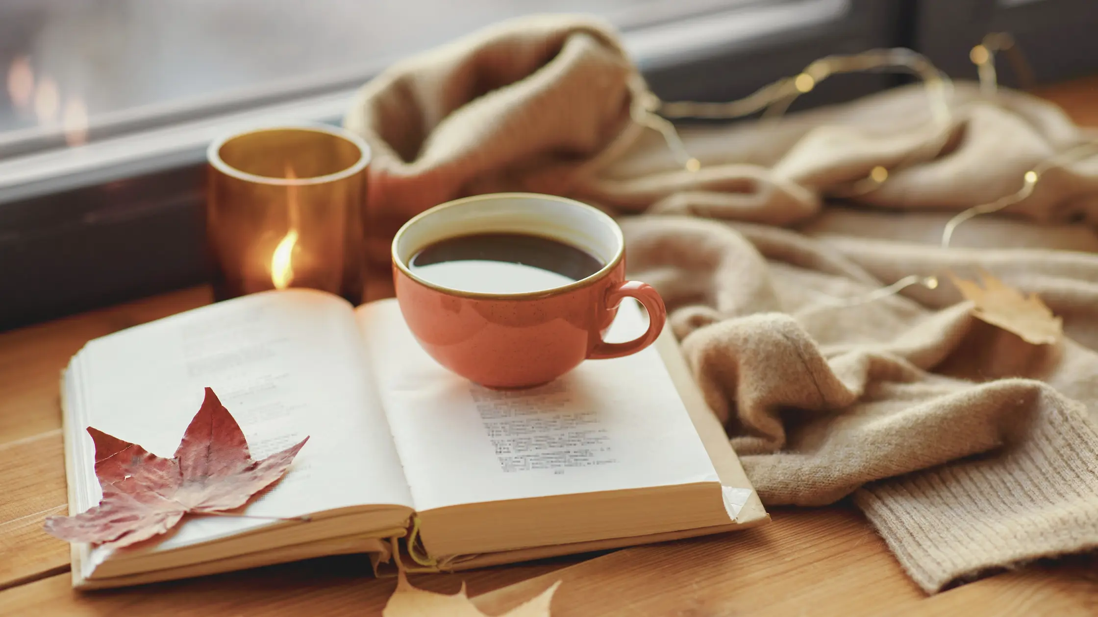 Un libro aperto e una tazza di caffè su un tavolo, simbolo di una pausa rilassante e disconnessa durante una giornata di digital detox