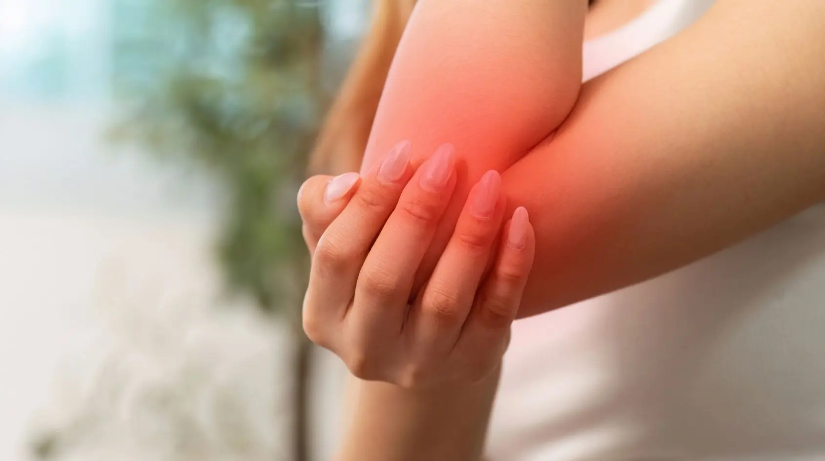 Donna che avverte dolore muscolare al gomito e si massaggia a casa, esempio realistico di DOMS post allenamento