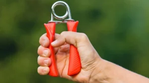 Mano che stringe un hand grip esercizi rosso per migliorare la forza di presa