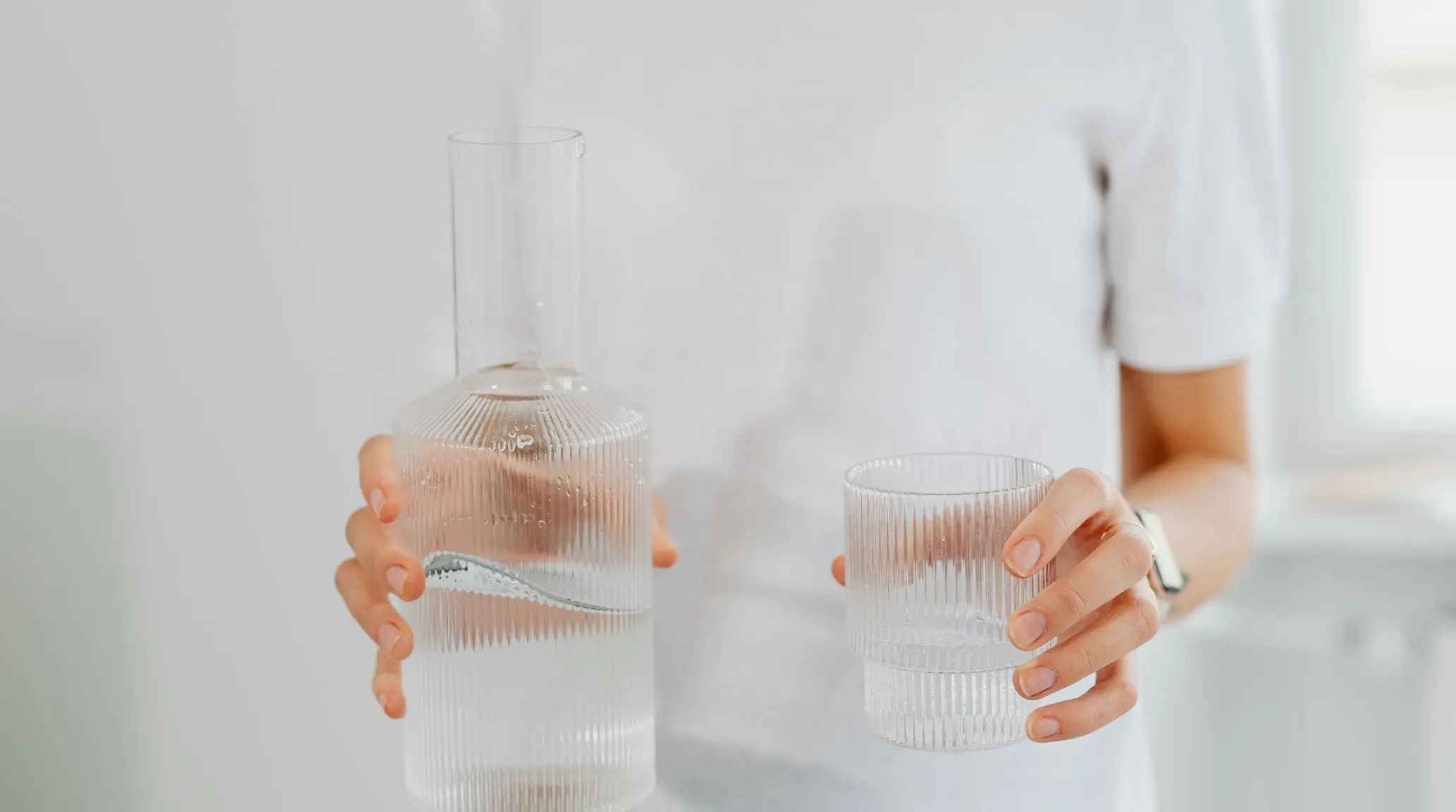 Persona che versa acqua in un bicchiere per reintegrare liquidi ed elettroliti dopo l’attività fisica, con focus su potassio e sport