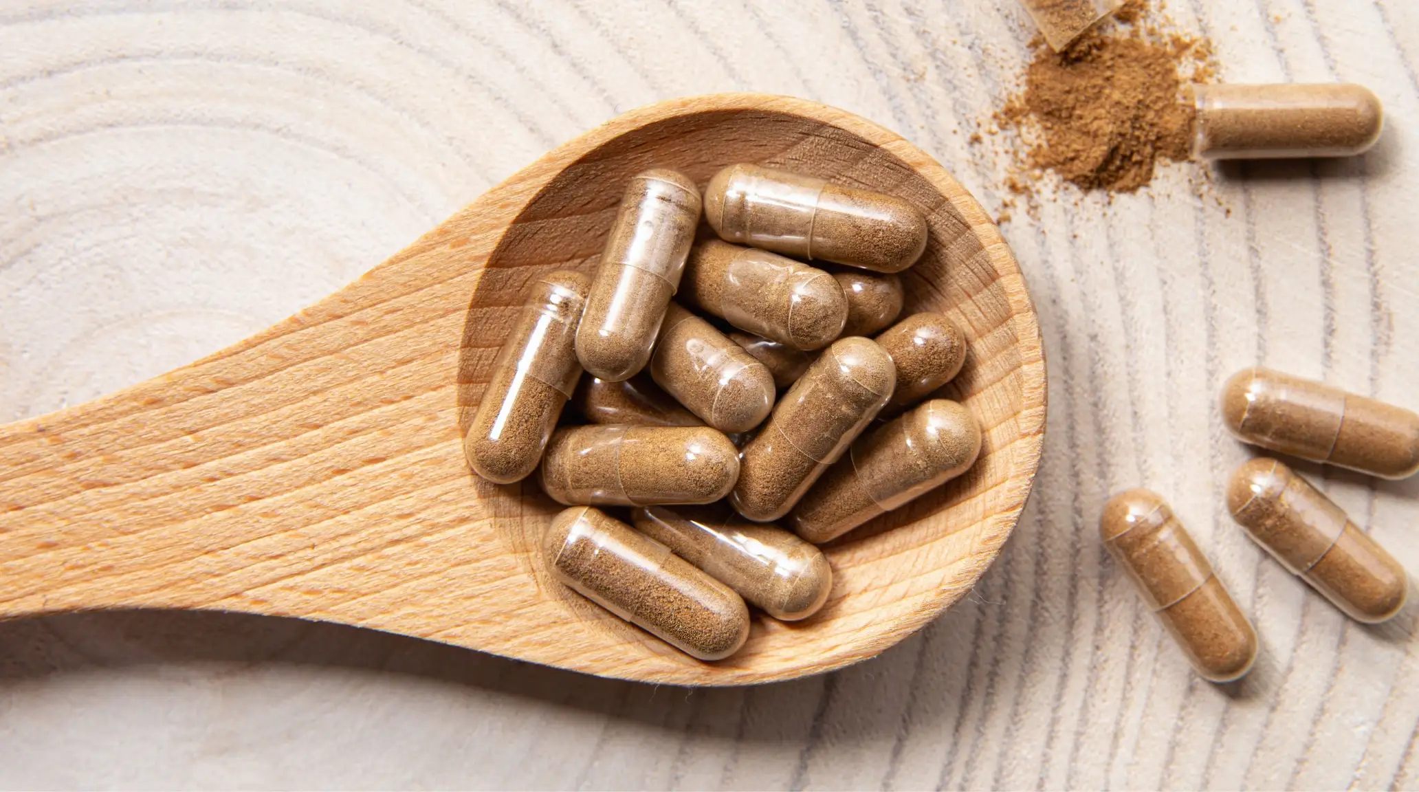 Capsule di Ashwagandha in un cucchiaio di legno con polvere di estratto