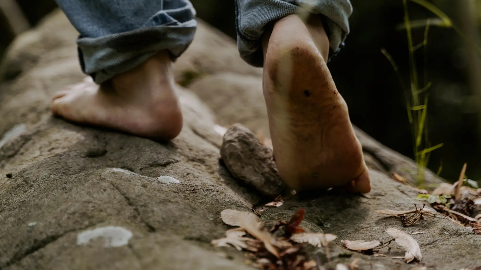 Primo piano di piedi nudi che camminano su un sentiero roccioso, con un piede sollevato durante il passo
