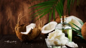 Bottiglia di olio trasparente, noci di cocco aperte e ciotola con grasso di cocco su un tavolo di legno