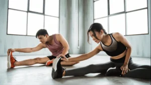 Donna e uomo eseguono esercizi di stretching a terra in palestra