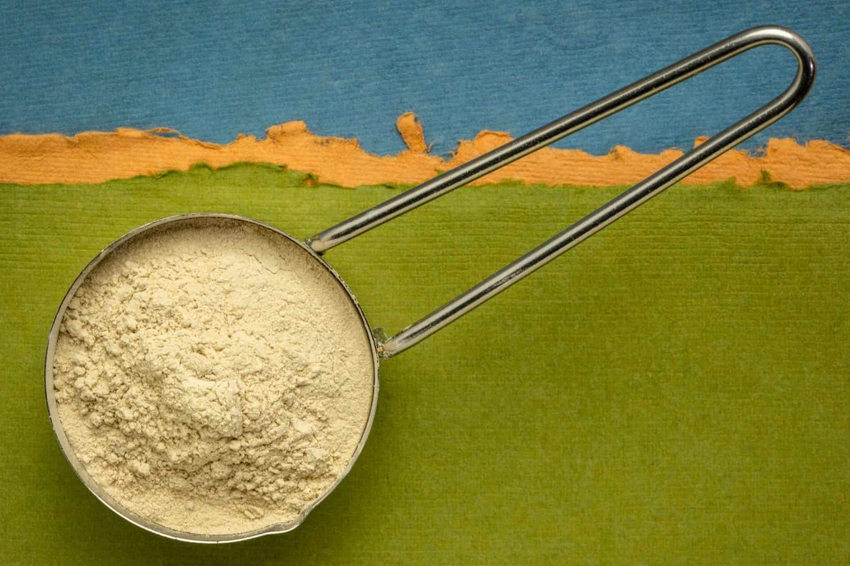 Pentolino con polvere di ashwagandha su sfondo verde e blu